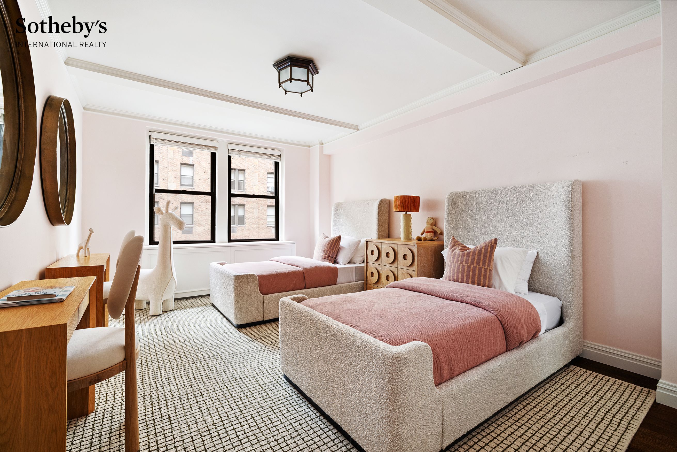 Bedroom with twin upholstered beds, dusty rose bedding, patterned carpet, and two large windows.