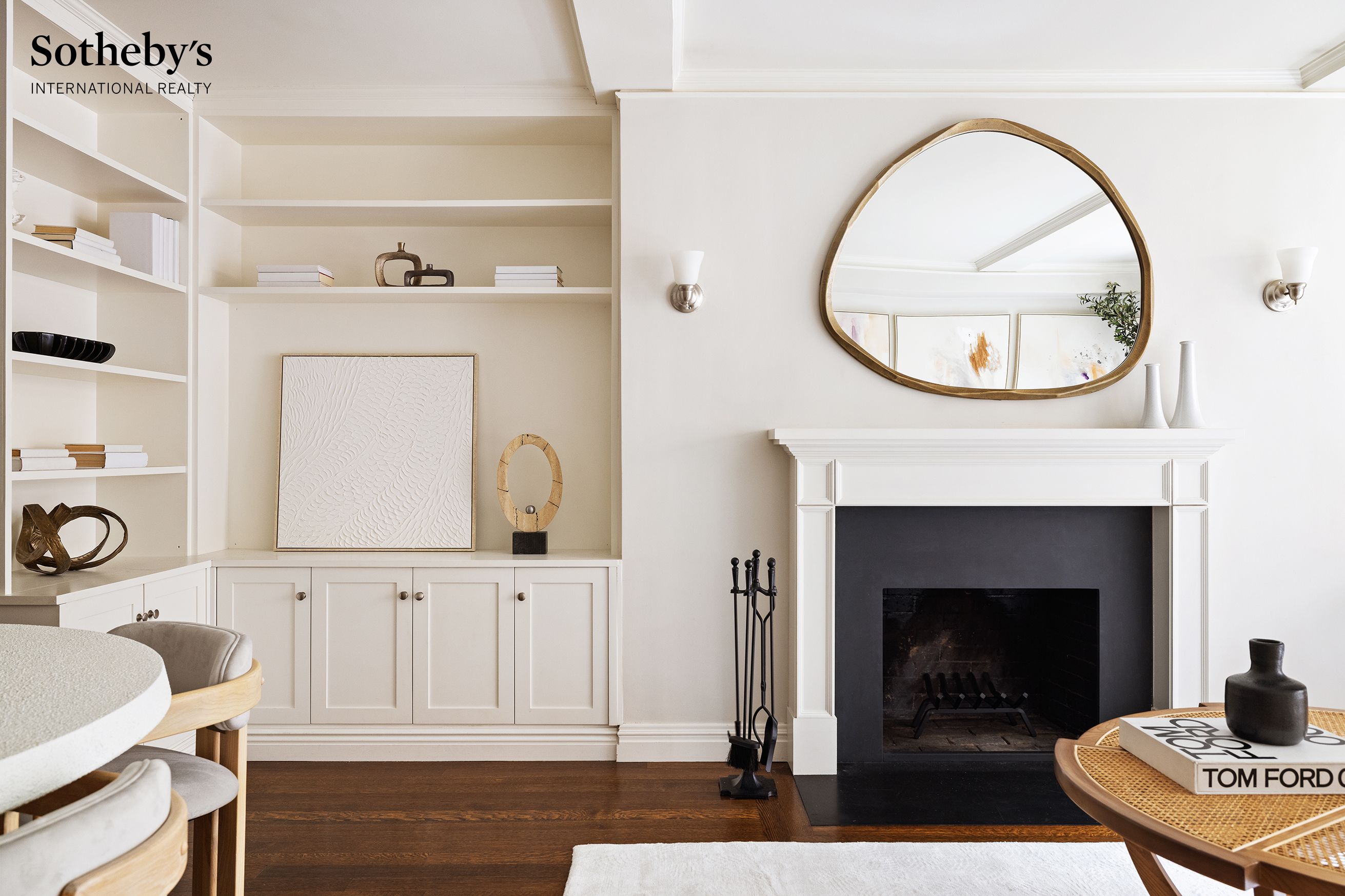 Staged living room with a white fireplace, built-in shelving, and an oval brass-framed mirror.