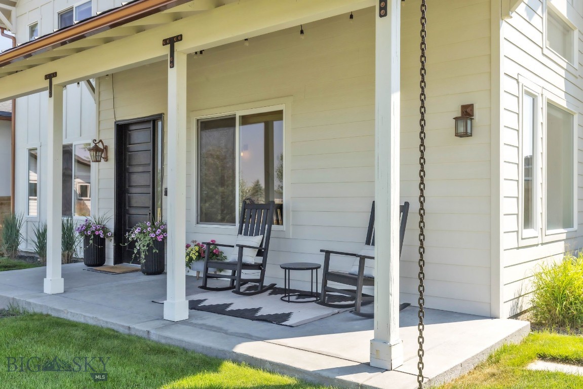 Covered front porch with rocking chairs, flower planters, and a black front door.