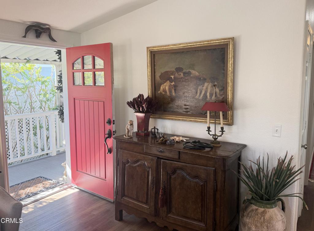 Entryway with a bright red open front door and dark wood console cabinet beneath framed artwork.