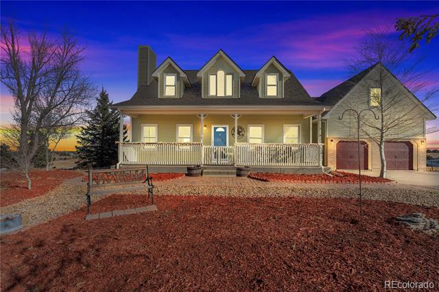 Two-story house at dusk with a covered porch, three dormers, and an attached garage.