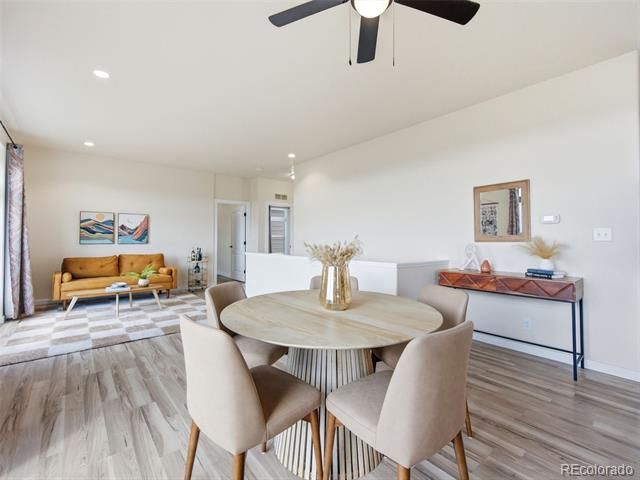Dining area with a round table and chairs beside a living room with a mustard-colored sofa.
