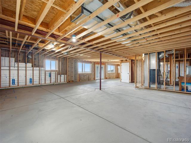 Unfinished interior with exposed wood framing, open wall studs, and a concrete floor.