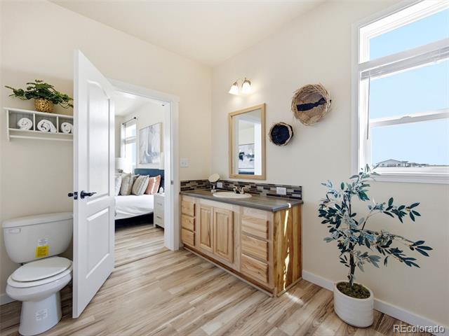 Bright bathroom with a wood vanity and large window overlooking open land.