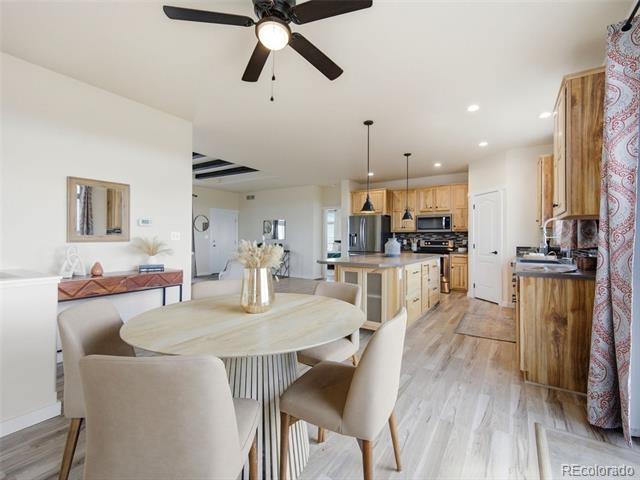 Dining area with a round table and upholstered chairs opening onto a kitchen with a wood island.