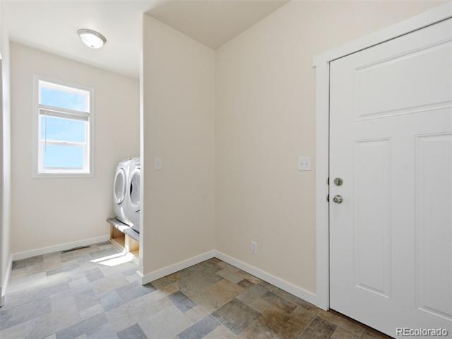 Tiled entry and laundry area with a white door, window, and washer and dryer.