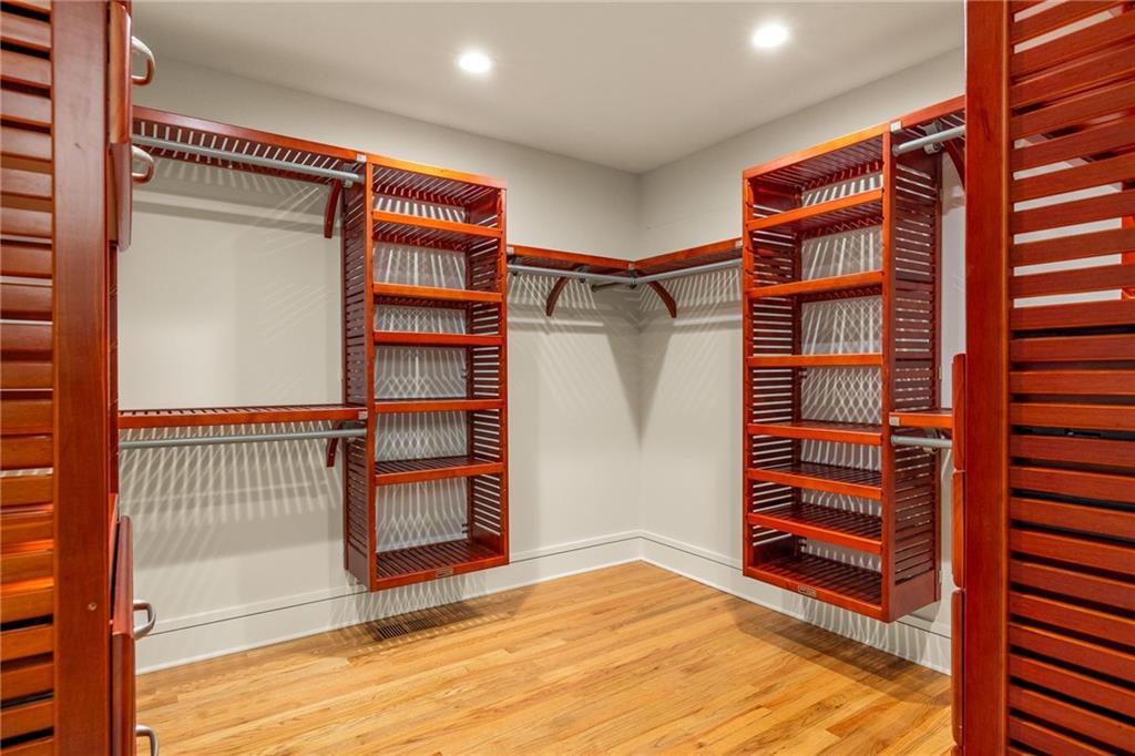 Walk-in closet with reddish-brown wooden shelving and hardwood floors.