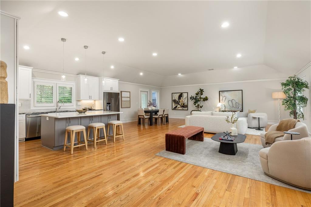 Open-plan living room and kitchen with a large island, hardwood floors, and neutral furnishings.