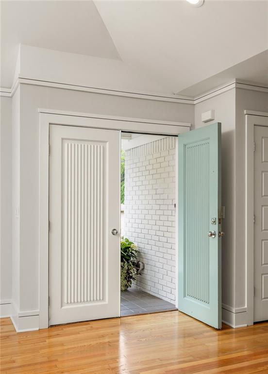 Entryway with open white and pale aqua doors, hardwood floors, and a white brick vestibule.