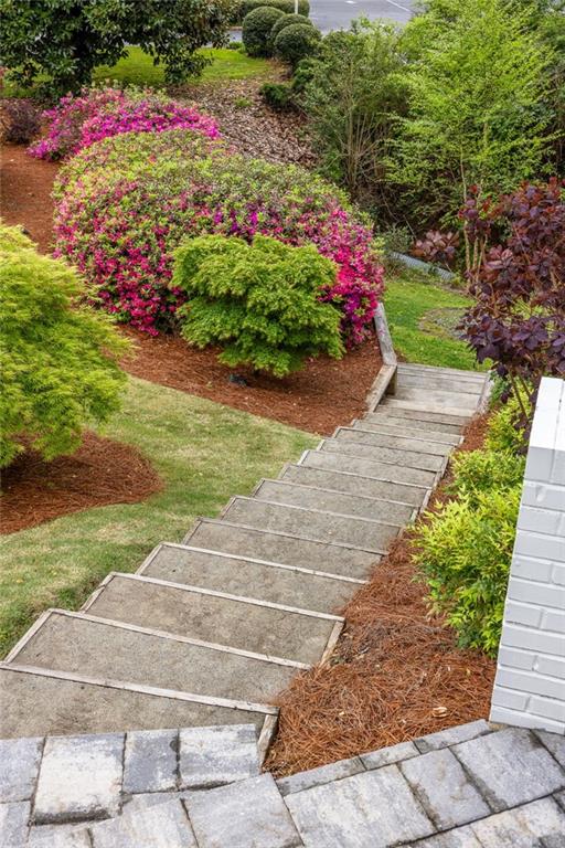 Concrete steps wind through landscaped beds of pink flowering shrubs toward the home.