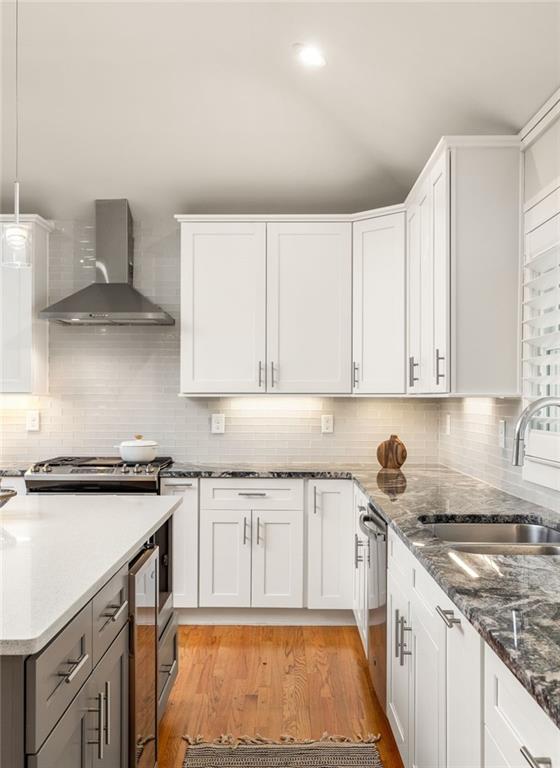 Kitchen with white cabinets, granite countertops, stainless steel appliances, and hardwood floors.