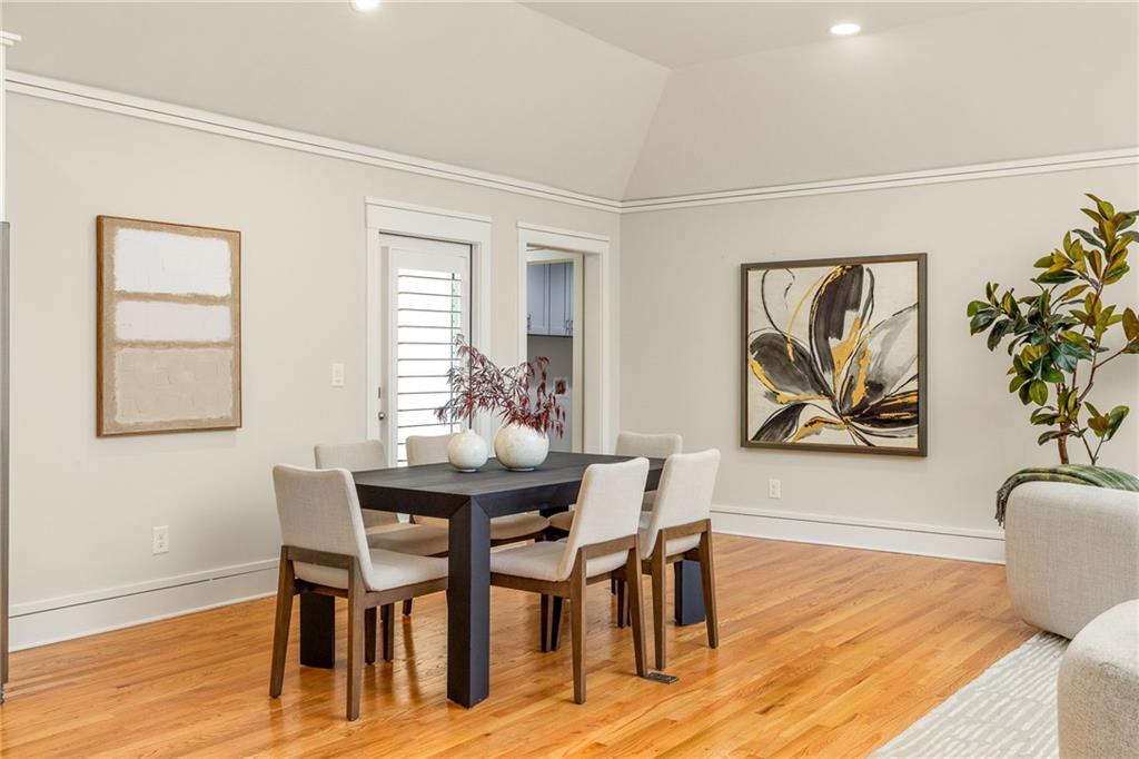 Dining room with a dark table, upholstered chairs, hardwood floors, and a vaulted ceiling.