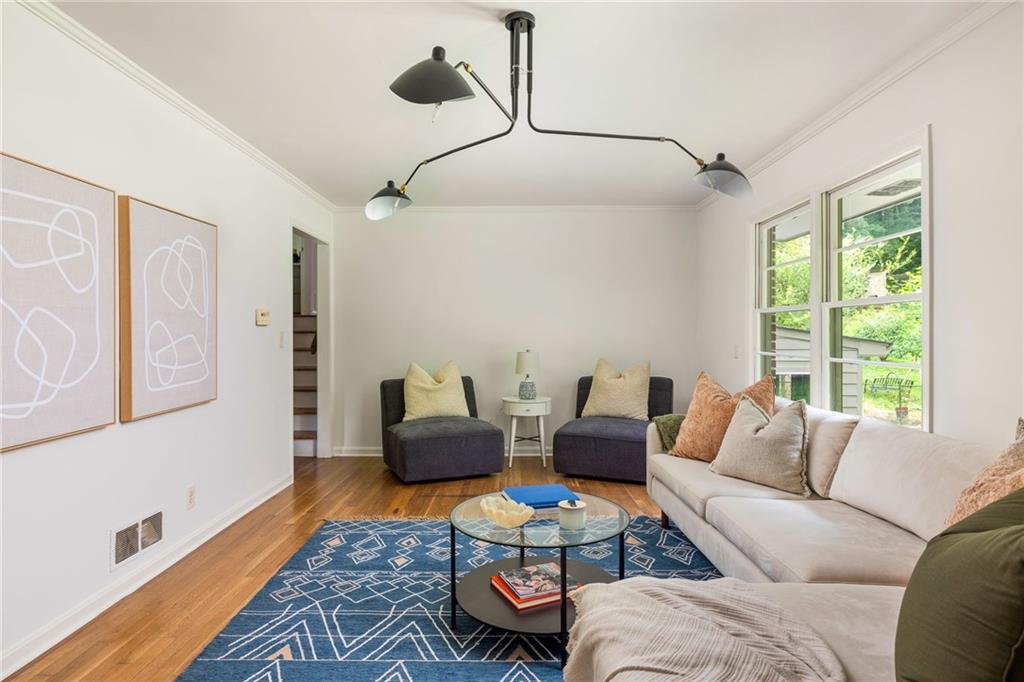 Living room with a white sectional, dark lounge chairs, and a blue geometric rug beside large windows.