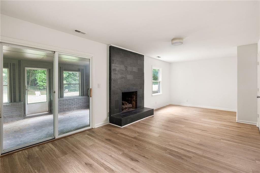 Vacant living room with a dark tiled fireplace and sliding glass doors to an enclosed porch.