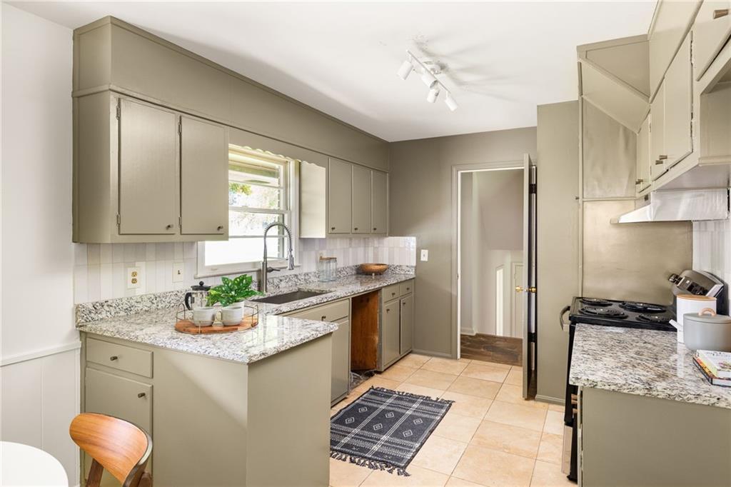 Kitchen with gray-green cabinets, granite counters, a breakfast peninsula, and a window above the sink.