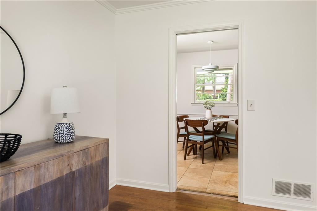 Dining room with a round wooden table, pendant light, and window overlooking greenery.