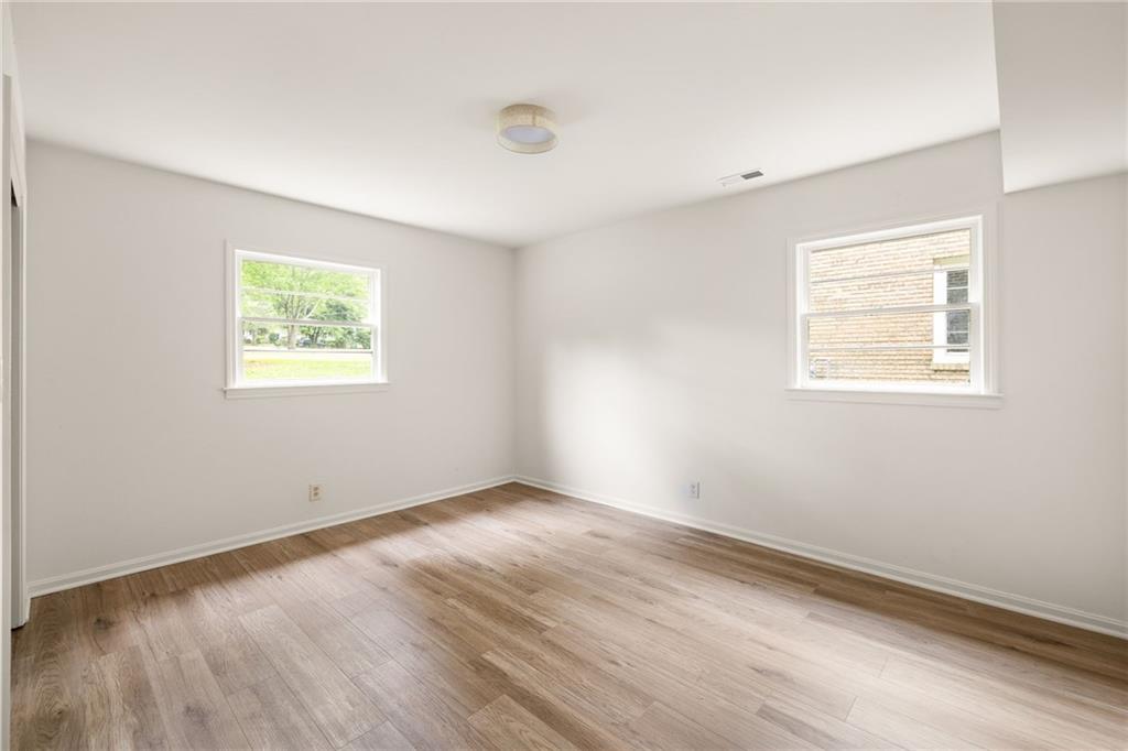 Empty room with wood-look flooring and two windows.