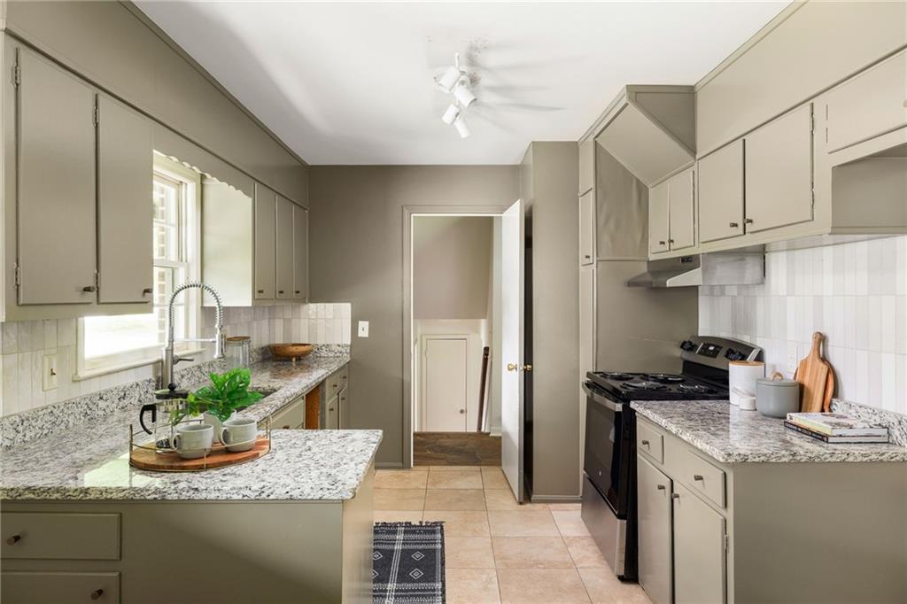 Kitchen with gray cabinets, granite countertops, a sink island, and black appliances.