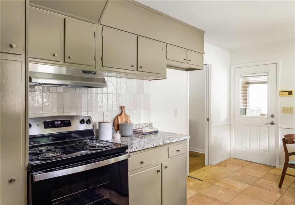Kitchen with cream cabinets, black electric range, granite counters, and a windowed exterior door.