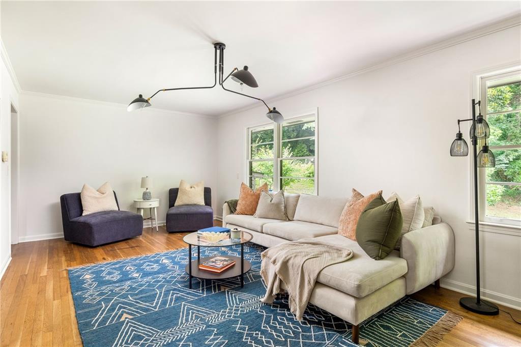 Living room with a cream sectional, dark accent chairs, blue geometric rug, and hardwood floors.
