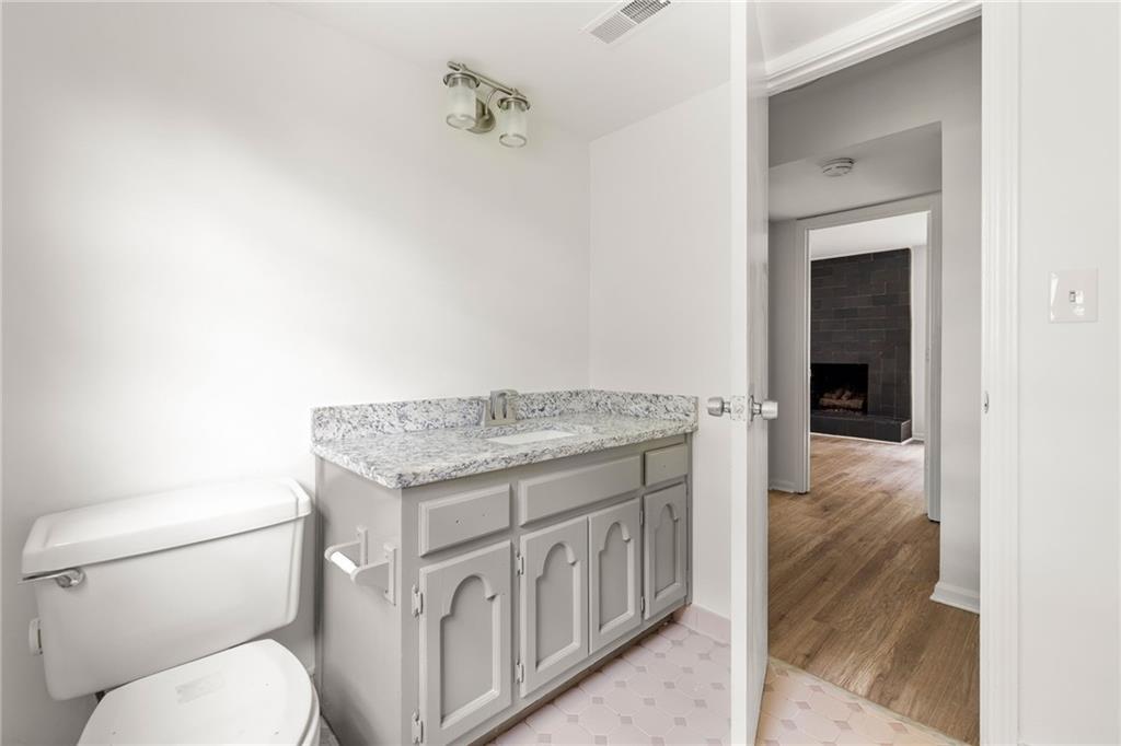 Bathroom with gray vanity and granite countertop, opening toward a living room fireplace.