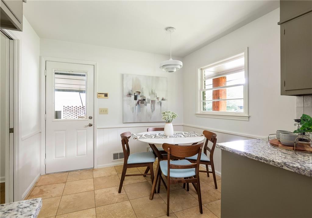 Kitchen dining nook with a round table, four wooden chairs, abstract art, and a bright window.