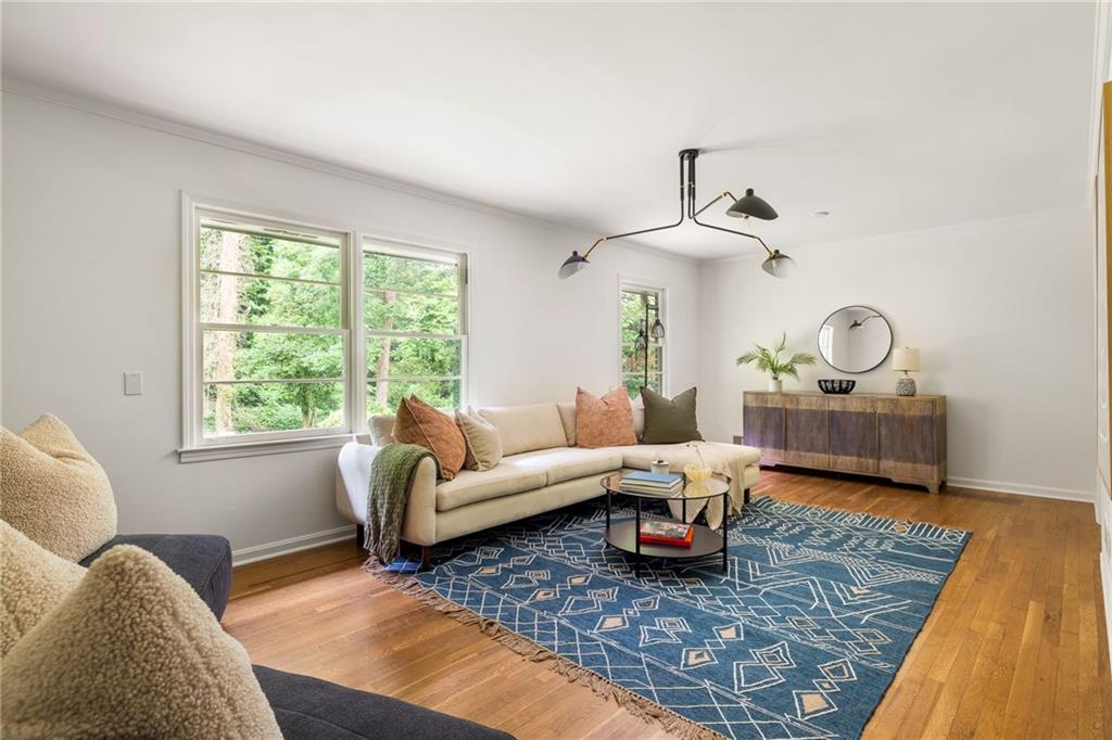 Living room with a cream sectional, blue geometric rug, and large windows overlooking greenery.