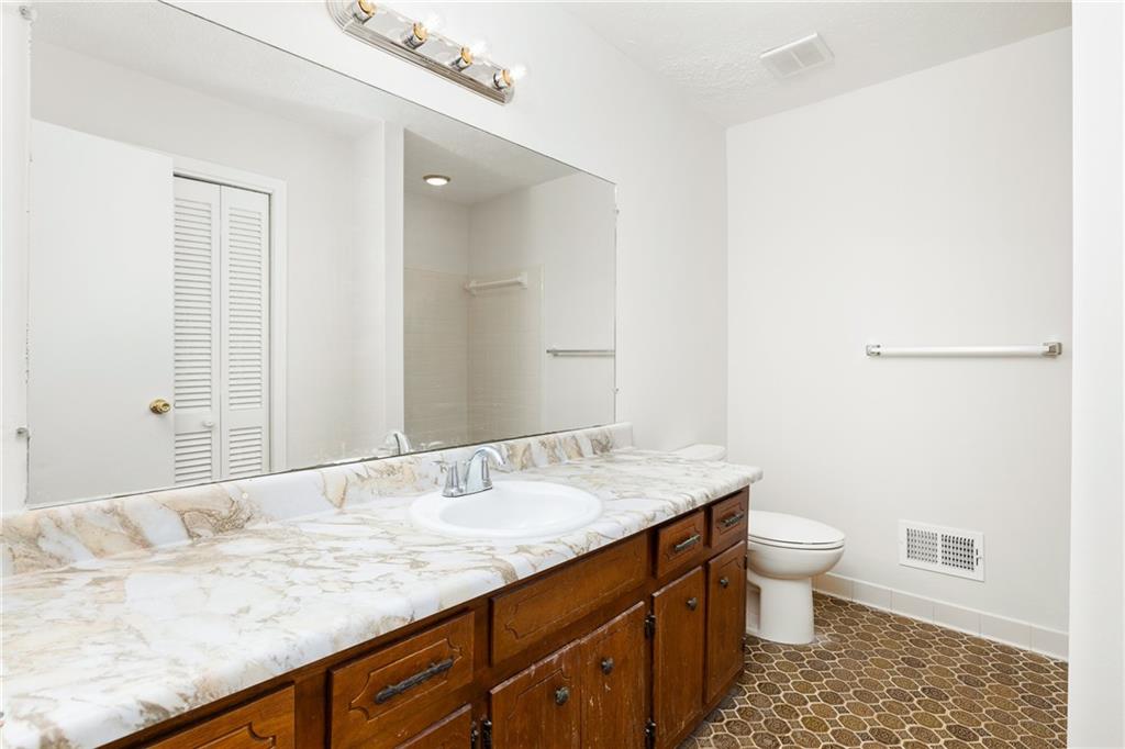 Bathroom with a long marble-patterned vanity, dark wood cabinets, large mirror, and patterned tile floor.