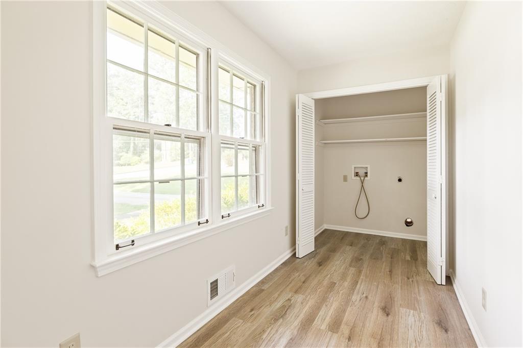 Empty laundry room with large windows and an open closet with washer hookups.