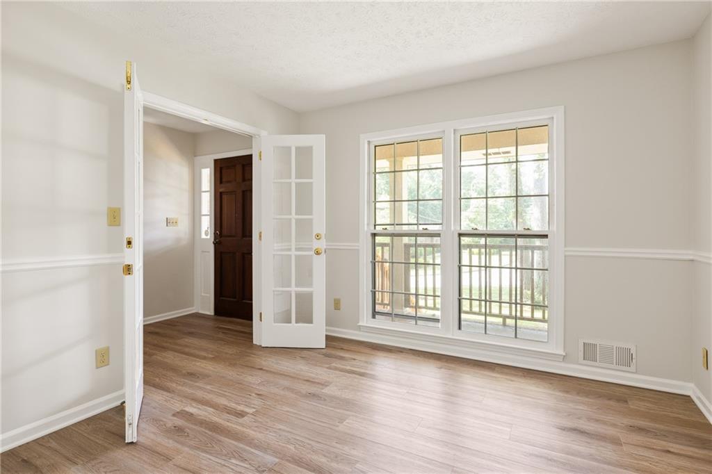 Empty room with wood-look flooring, a dark entry door, and two large windows.