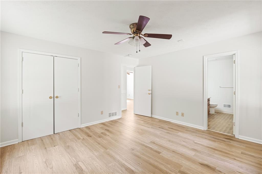 Empty bedroom with light wood-look floors, a ceiling fan, and double closet doors.