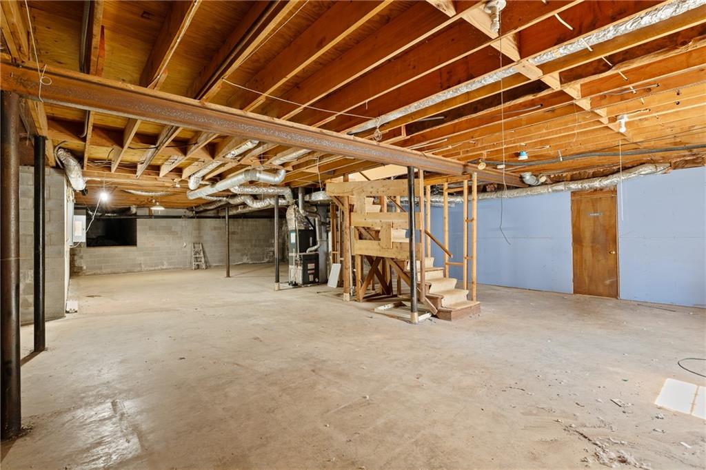 Unfinished basement with exposed ceiling joists, concrete floor, and a central staircase.