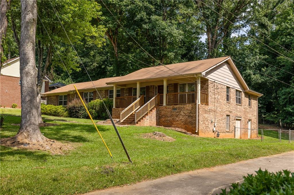 Brick ranch house with a raised covered porch and front steps on a sloping lawn