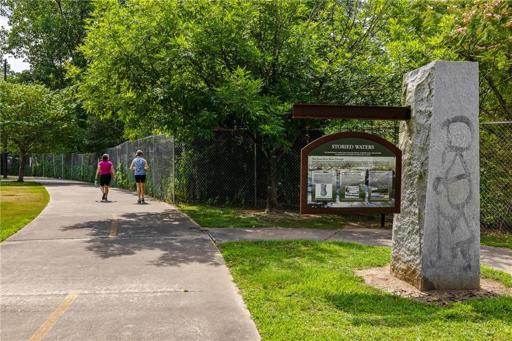 Paved walking trail beside a Storied Waters interpretive sign, with two women walking.