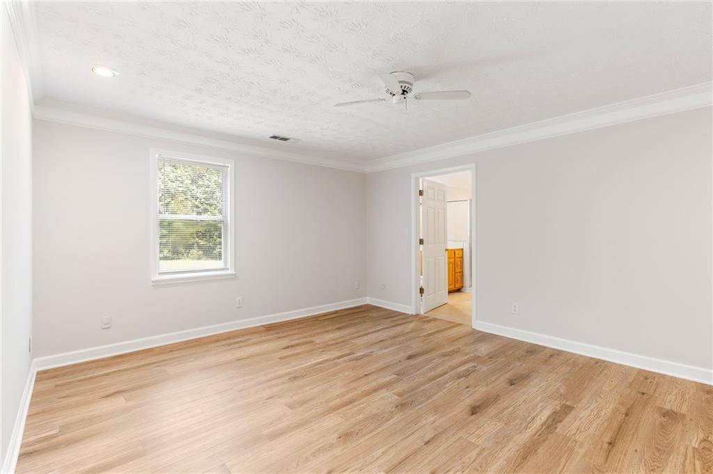 Empty room with light wood floors, a window, and a ceiling fan