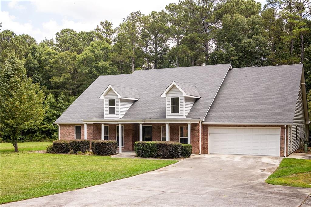 Brick-and-siding house with two dormers, an attached garage, and a wide driveway.