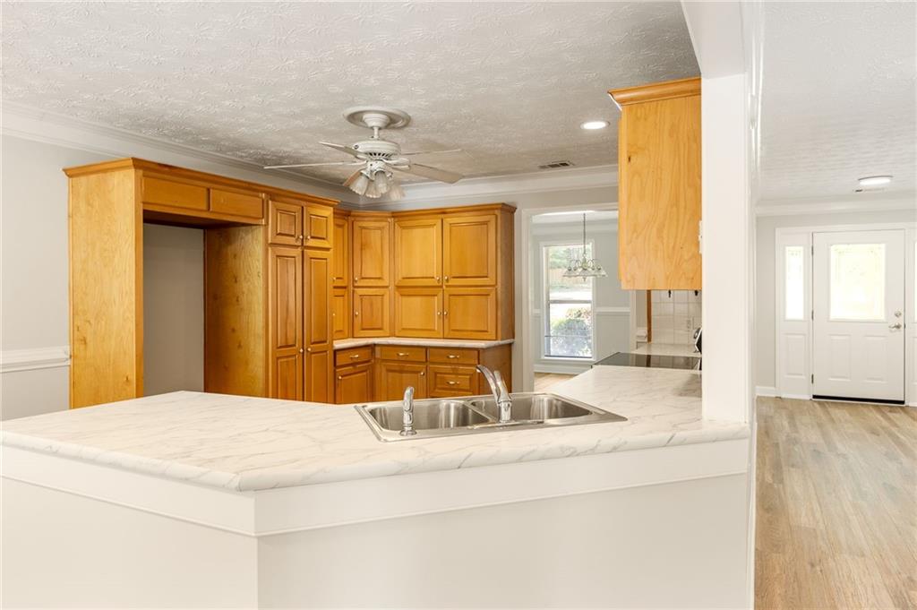 Empty kitchen with honey-colored cabinets and a large white peninsula with a double sink.