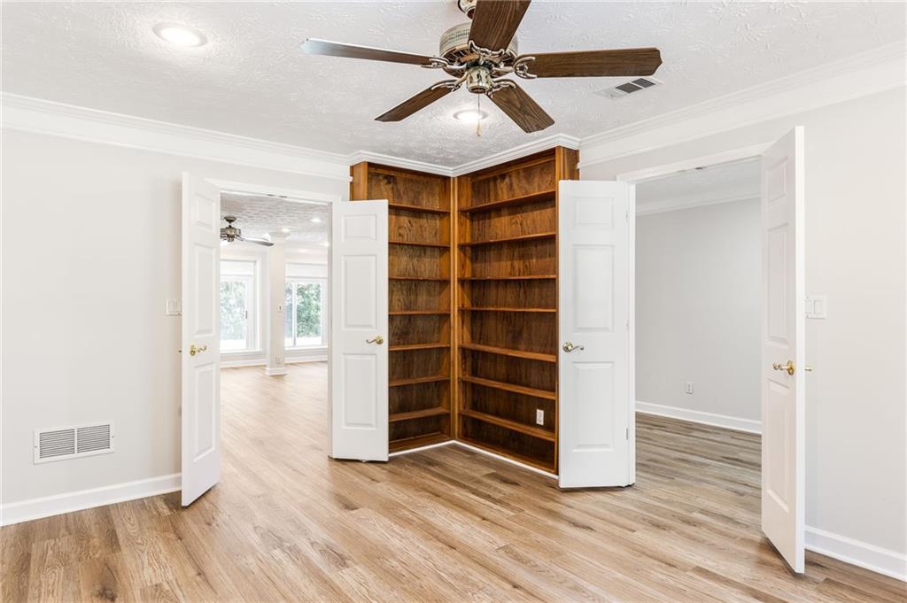 Room with corner built-in wooden bookshelves, wood-look flooring, and open double doors.