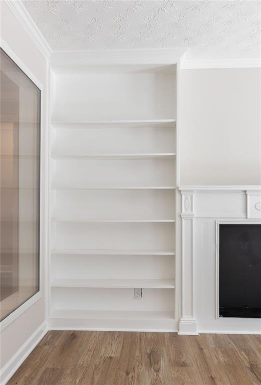 Built-in white shelves beside a fireplace in a room with hardwood floors.