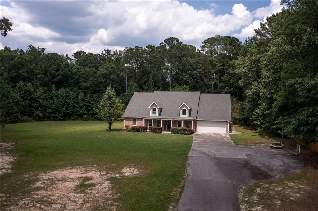 House with two front dormers, an attached garage, broad lawn, and long driveway.