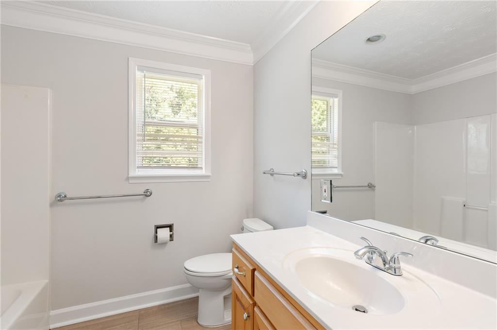 Bathroom with a wood-front vanity, white sink, and window with blinds.
