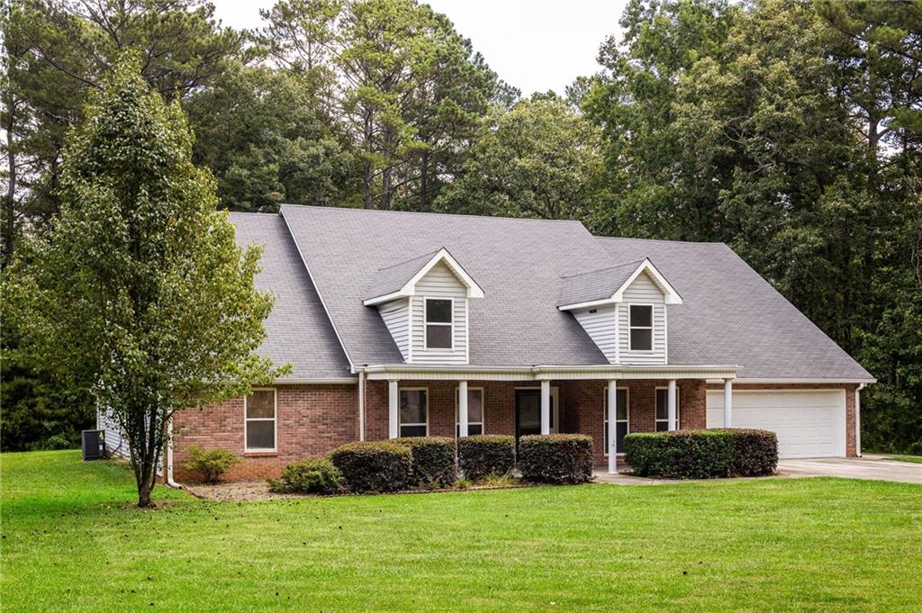 Brick-and-siding house with two dormers, a covered porch, and an attached garage on a broad lawn.