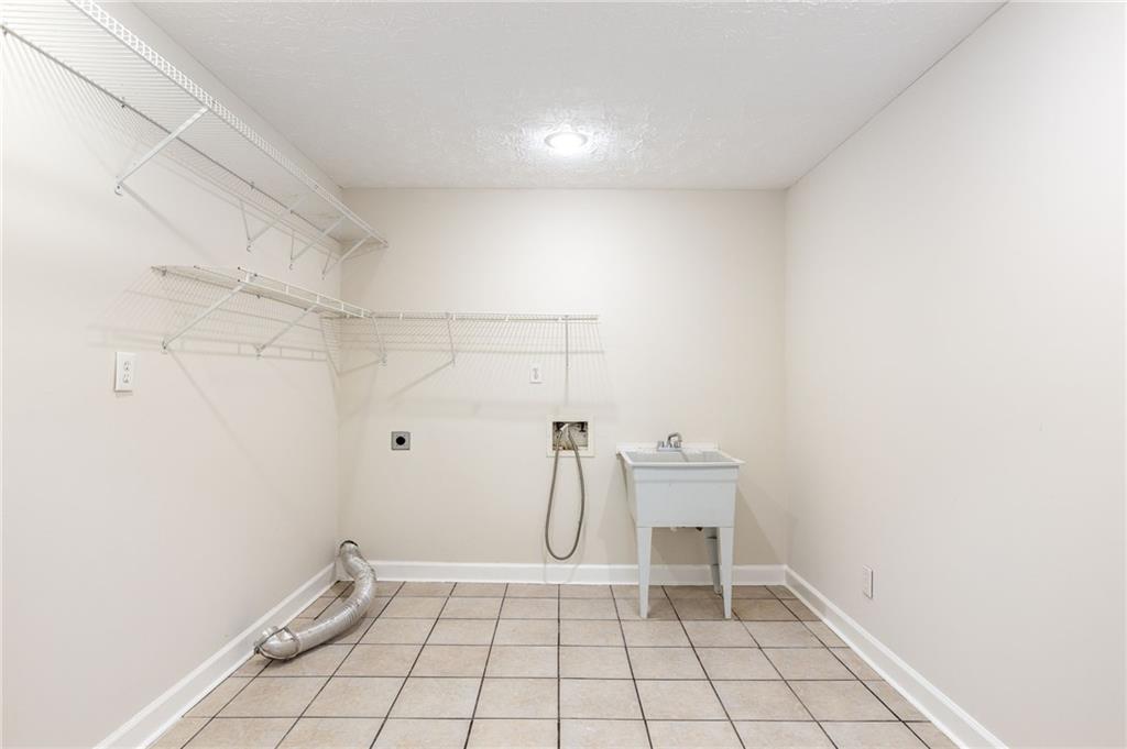 Empty laundry room with wire shelving, washer hookups, and a utility sink.