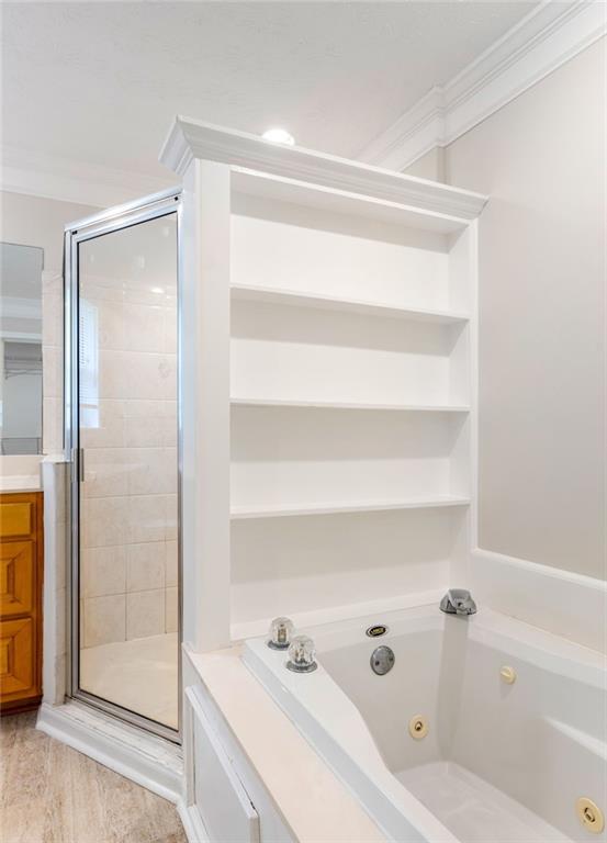 Bathroom with a soaking tub, open built-in shelves, and a glass-enclosed shower.