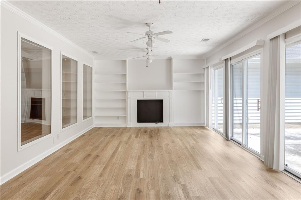 Empty living room with white built-in shelves, a fireplace, and sliding glass doors to a patio.