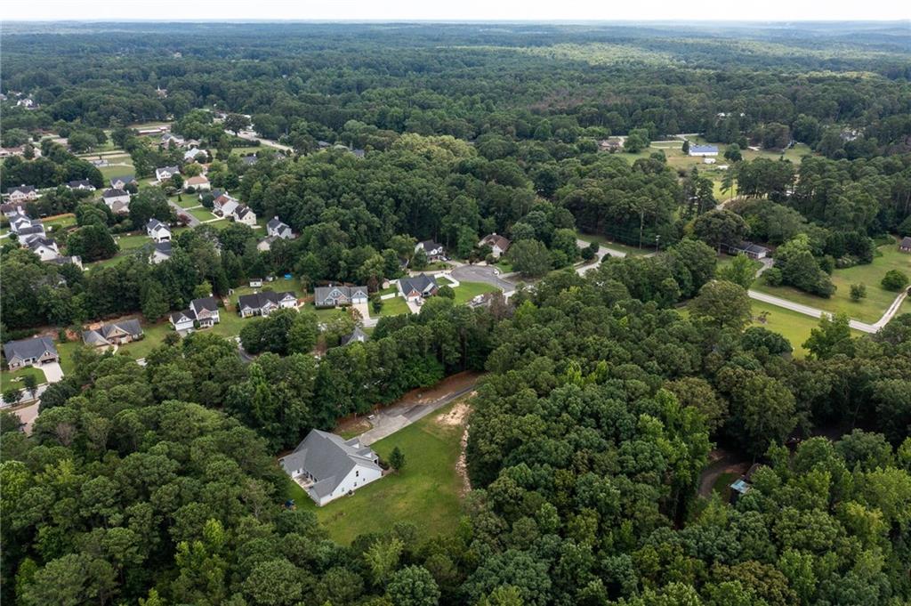 White house on a green lot amid dense trees and a wooded neighborhood.