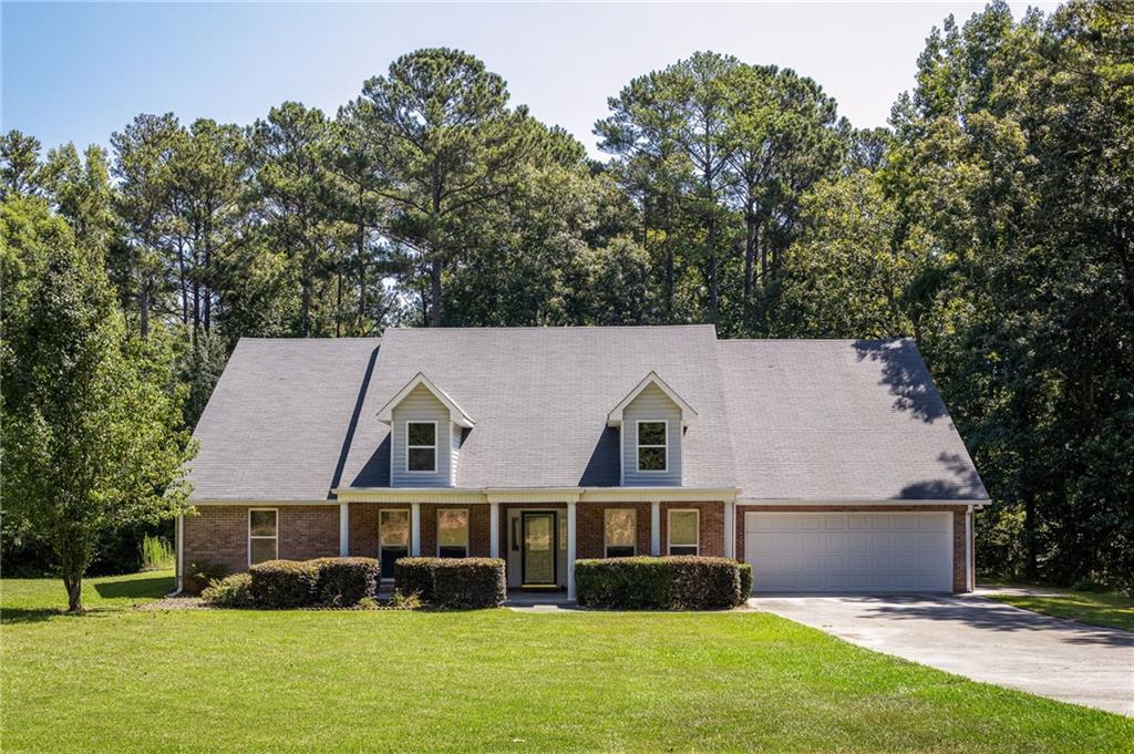 Brick-and-siding house with two dormers, an attached garage, and a tree-lined lawn.
