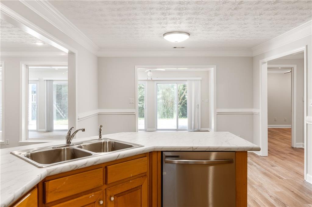 Kitchen with warm wood cabinets, marble-look counters, double-basin sink, and stainless steel dishwasher.