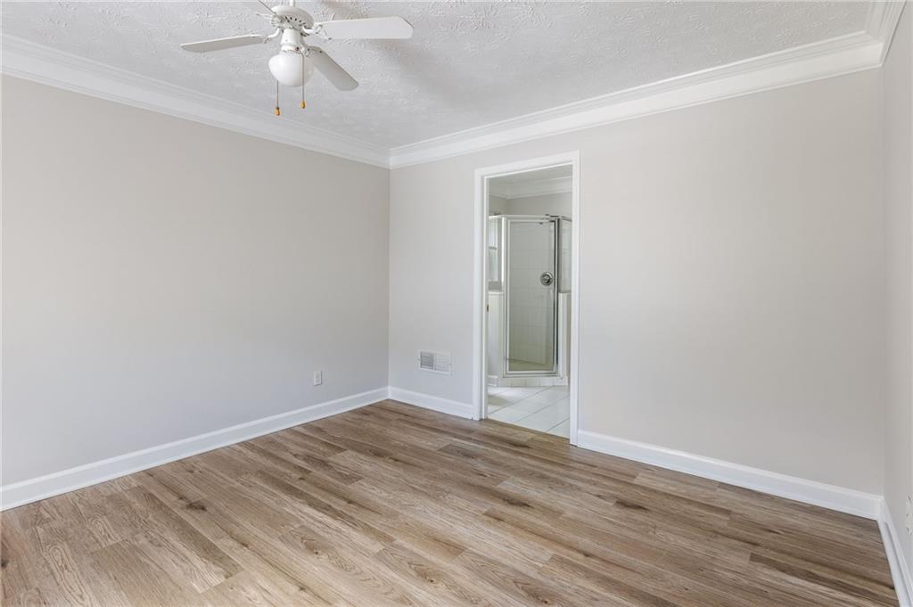 Empty bedroom with wood-look flooring and a doorway to an adjoining bathroom.