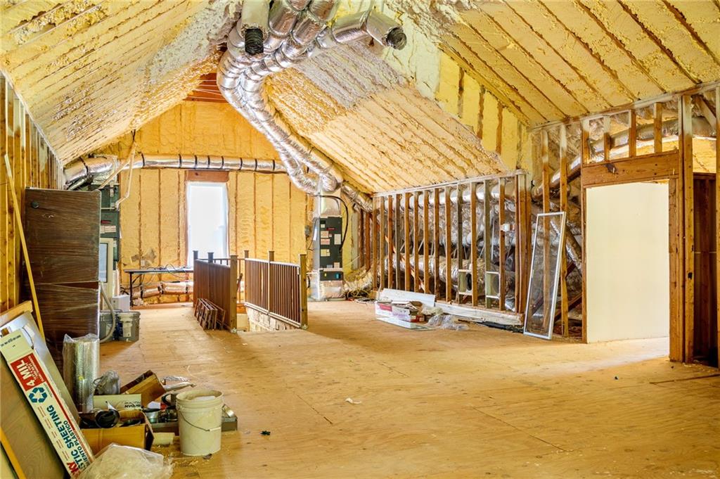 Unfinished attic with exposed framing, spray-foam insulation, and visible HVAC ducts.